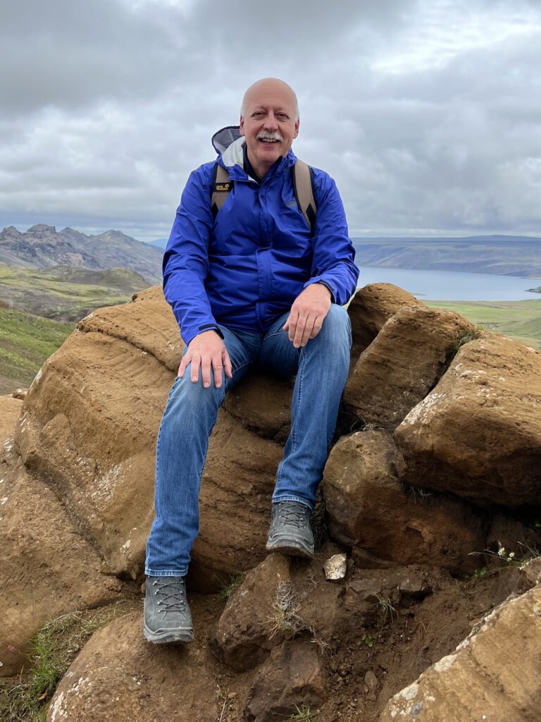 Christian Nusser sitzt in Island auf einem Stein vor einem See