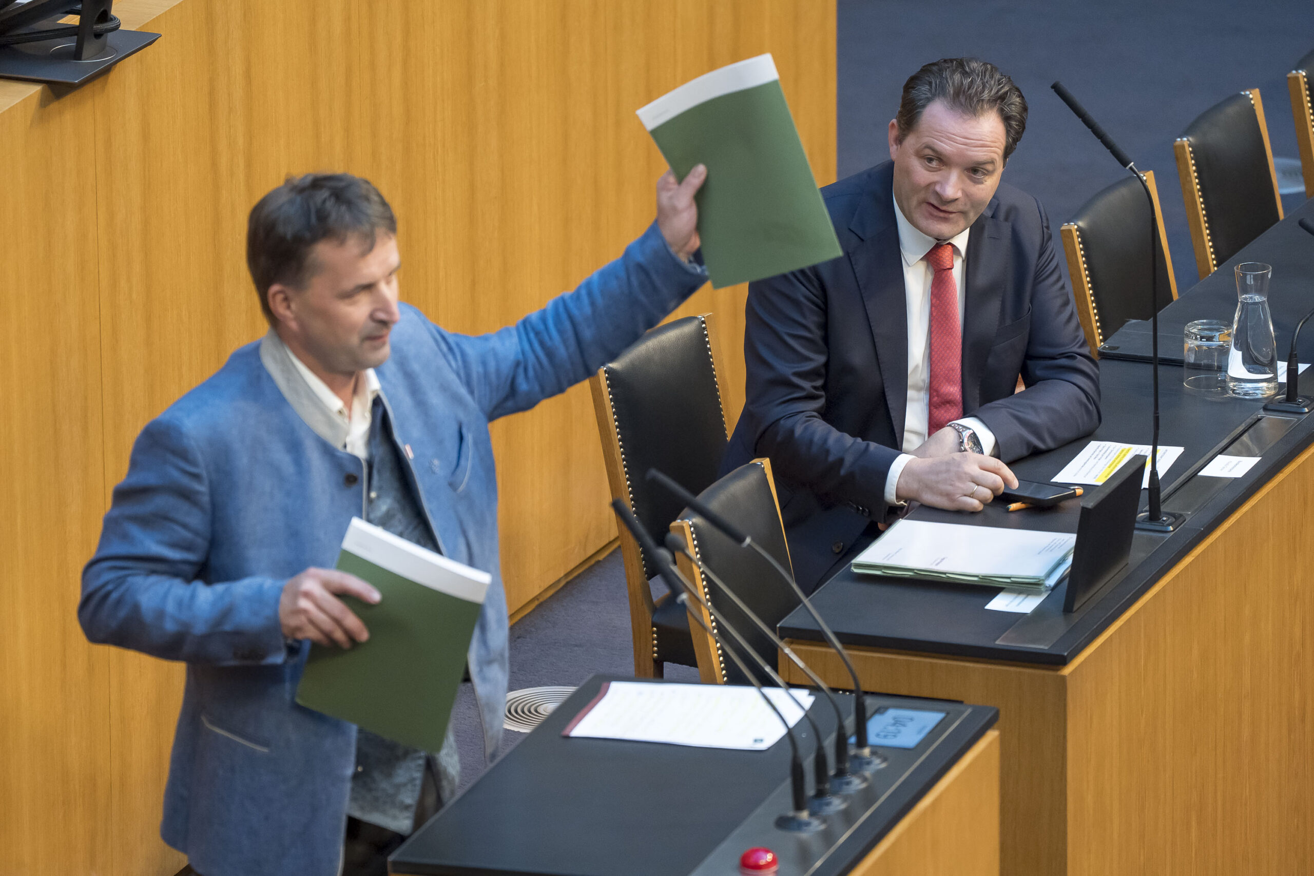 FPÖ-Abgeordneter Albert Royer hält den Grünen Bericht in der Hand, im Hintergrund Umweltminister Norbert Totschnig